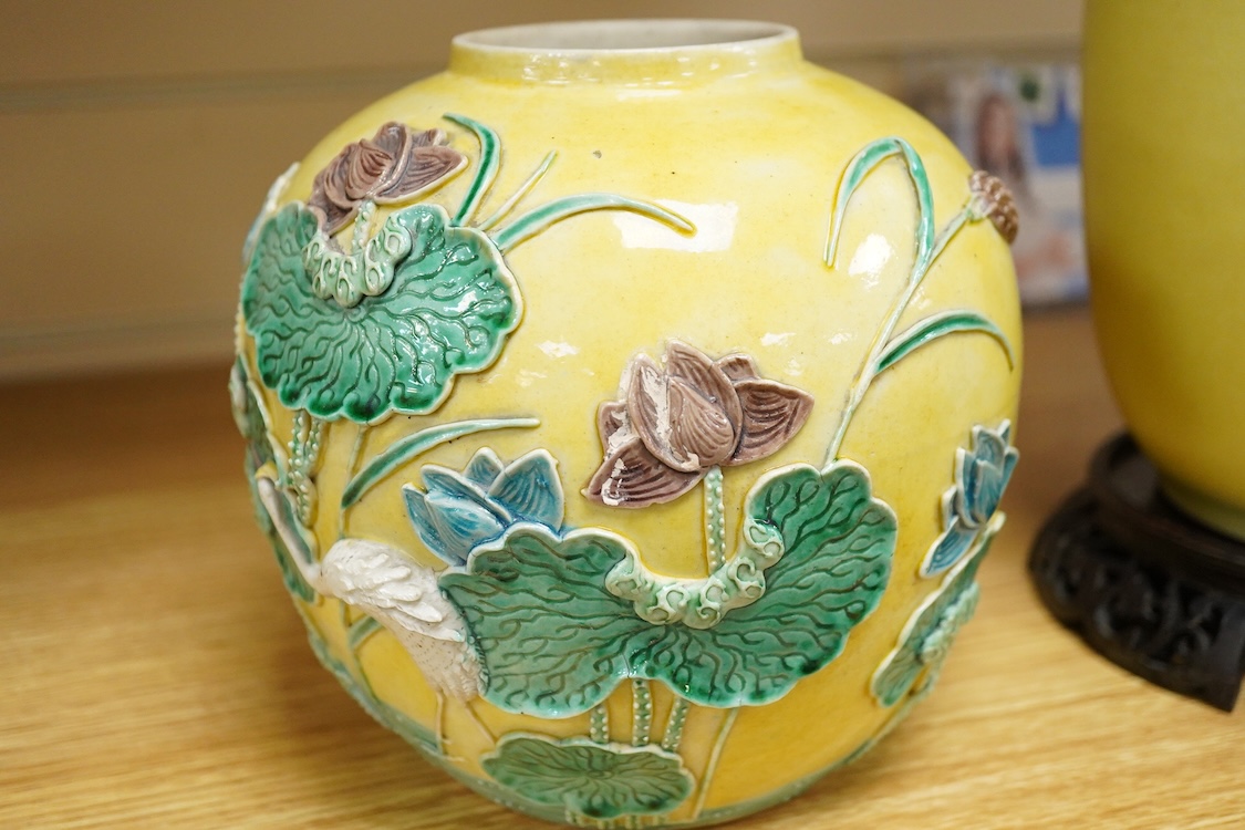 A Chinese yellow ground vase and carved hardwood stand and a Chinese sancai glazed jar, decorated in relief, both early 20th century, largest 25cm high